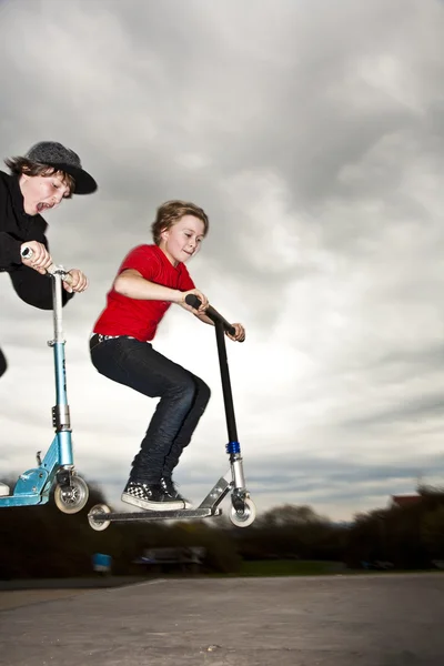 Niño saltando con un scooter sobre una rampa — Foto de Stock