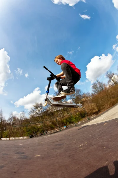 Мальчику нравится кататься на скутере и прыгать — стоковое фото
