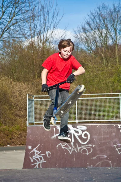 Jongen geniet zijn scooter rijden en springen — Stockfoto