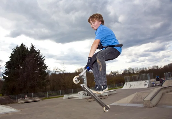 Çocuk onun scooter sürme ve atlama sahiptir — Stok fotoğraf