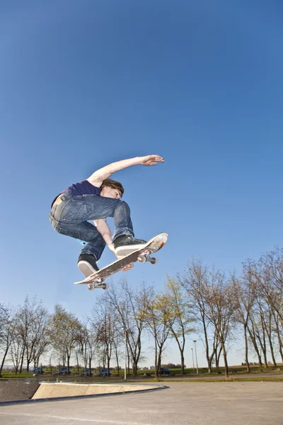Rapaz com prancha de skate vai para o ar — Fotografia de Stock