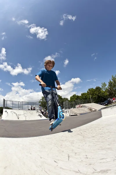 Pojken har kul med skoter i skateboardpark — Stockfoto