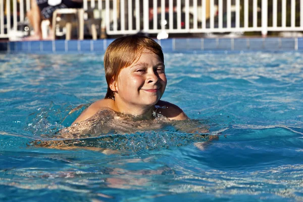 Criança feliz está nadando na piscina — Fotografia de Stock