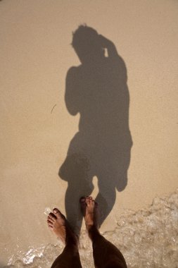 Man is throwing shadow to the fine sand of the beach, showing th clipart