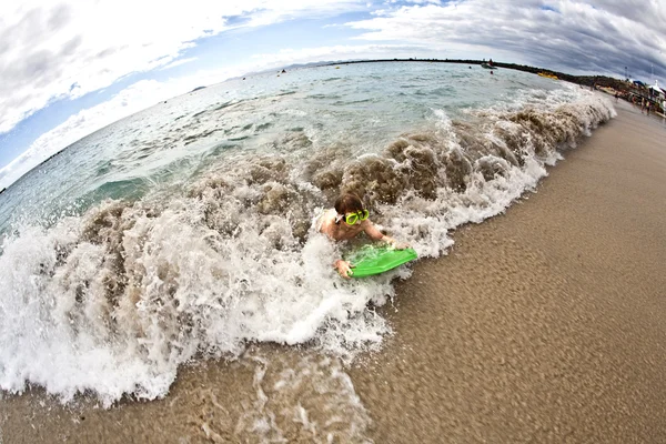 Garoto se diverte na praia nas ondas — Fotografia de Stock