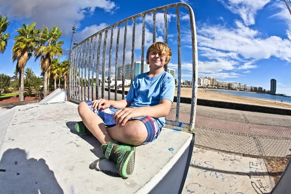 Милий хлопчик сидить у скейт-парку — стокове фото