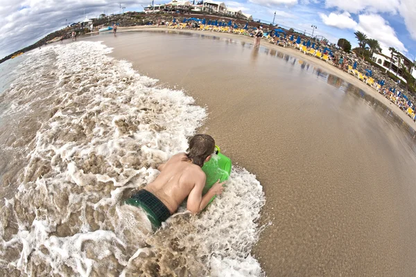 Garoto se diverte na praia nas ondas — Fotografia de Stock
