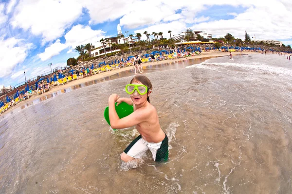 Pojken har kul på stranden i vågor — Stockfoto