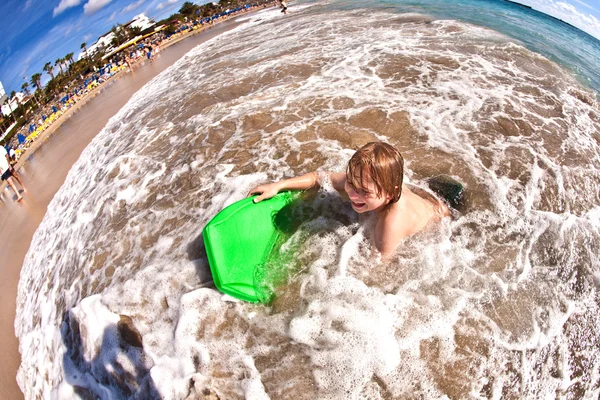 Pojken har kul med surfbräda i vågor — Stockfoto