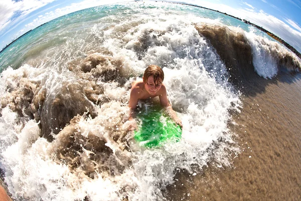 Chłopiec ma zabawy z deski surfingowej, w fale — Zdjęcie stockowe