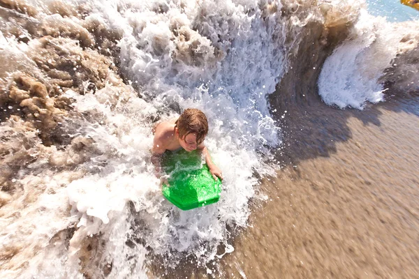 Jongen heeft plezier met de surfplank in de golven — Stockfoto