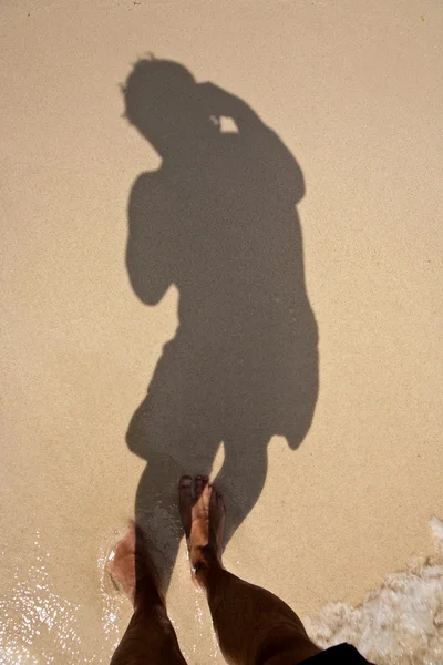 L'homme jette de l'ombre sur le sable fin de la plage, montrant — Photo