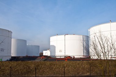 White tanks in tank farm with blue sky clipart