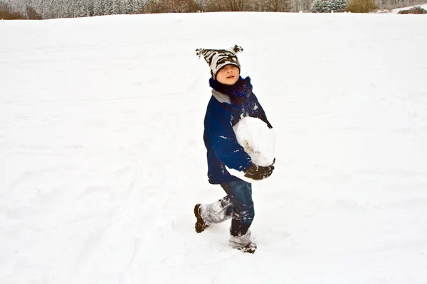 Rapaz carregando uma enorme bola de neve — Fotografia de Stock