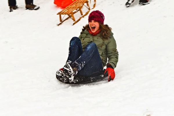Flicka pulka ner för backen på snö på vintern — Stockfoto