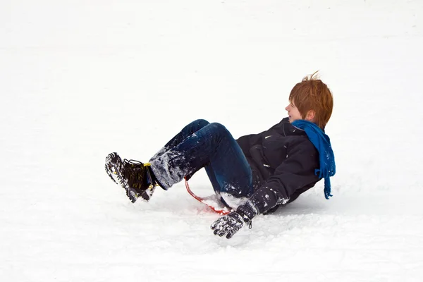 Criança escorregando pela colina na neve, inverno branco — Fotografia de Stock