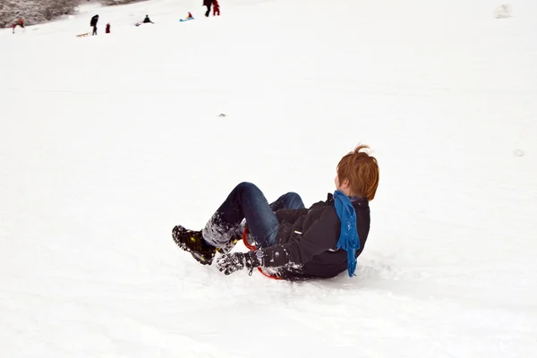Bambini slittano giù per la collina nella neve, bianco inverno — Foto Stock