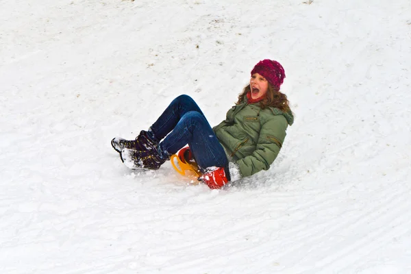 Meisje sleeën naar beneden de heuvel op sneeuw — Stockfoto