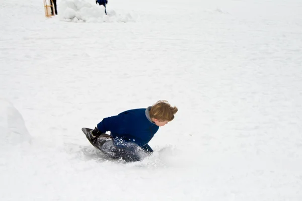 Dítě je sáňkování dolů z kopce v zimě sníh, bílá — Stock fotografie