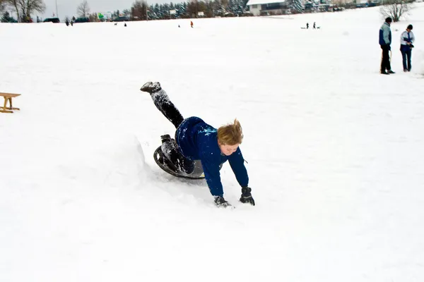 Criança está descendo a colina na neve, inverno branco — Fotografia de Stock