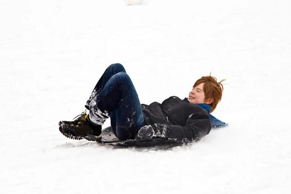 Niño bajando en trineo por la colina en nieve, invierno blanco — Foto de Stock