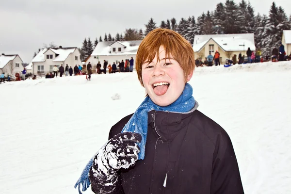 Мальчик с рыжими волосами наслаждается снегом — стоковое фото