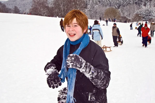 Chlapec s červenými vlasy, dovádění na sněhu — Stock fotografie