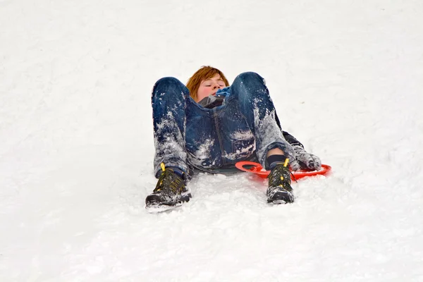 Menino deitado na neve se diverte — Fotografia de Stock