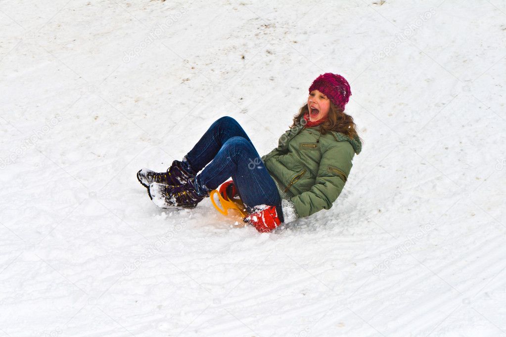 Girl sledging down the hill on snow