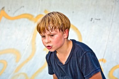 Boy rides scooter in a pipe at a skate park clipart