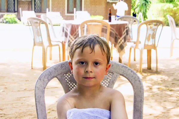 Мальчик, сидящий на территории отеля, наслаждается отдыхом — стоковое фото