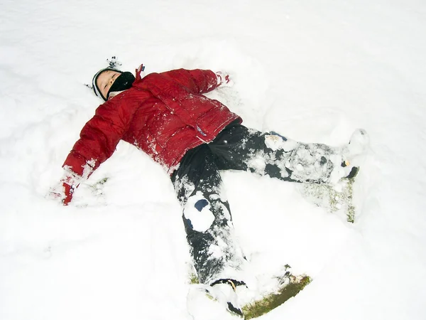 Jongen liggen in de sneeuw — Stockfoto