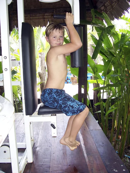 Criança faz exercícios de aptidão em equipamentos de treinamento borboleta — Fotografia de Stock