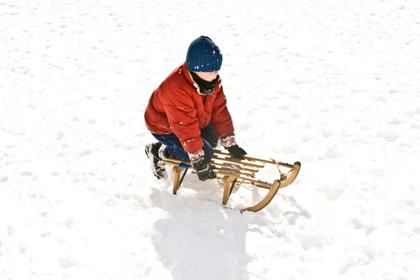 Młody chłopak sankach w dół wzgórza w zimie śnieg, biały — Zdjęcie stockowe