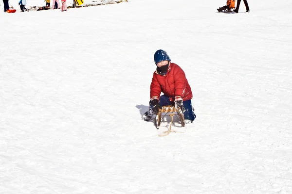 Szánkózás a hegyről a téli hó, fehér fiatal fiú — Stock Fotó
