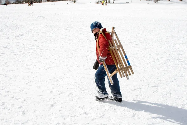 Menino jovem escorregando pela colina na neve, inverno branco — Fotografia de Stock