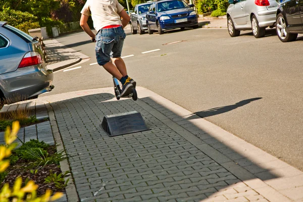 Мальчик ездит на скутере по тротуару — стоковое фото