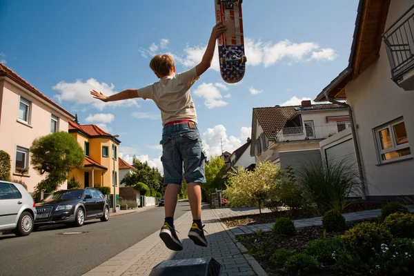 Menino está pulando e fazendo truques com o Scateboard no lado — Fotografia de Stock
