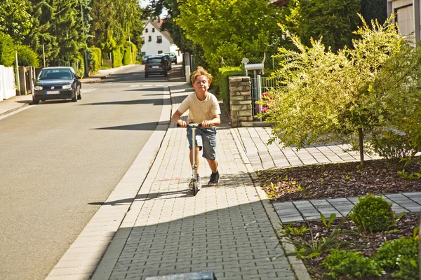 Poika pitää hauskaa scating jalkakäytävällä — kuvapankkivalokuva