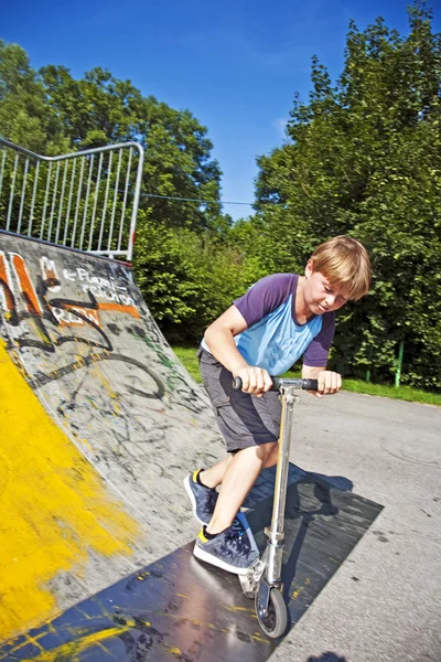 Мальчик ездит на скутере по трубе — стоковое фото