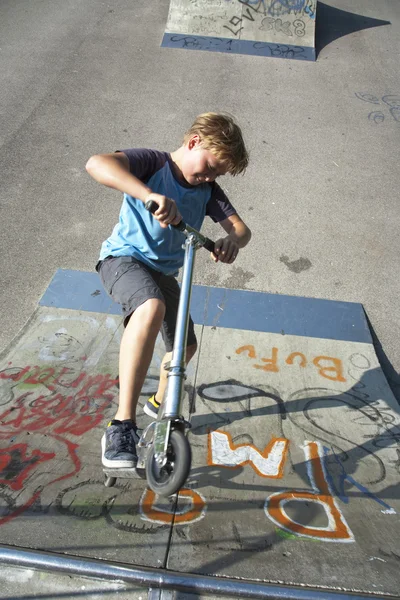 Αγόρι βόλτες σκούτερ σε ένα σωλήνα σε ένα πάρκο skate — Φωτογραφία Αρχείου