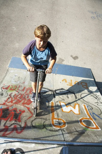 Chlapec se baví na koloběžce v scating na skateparku — Stock fotografie