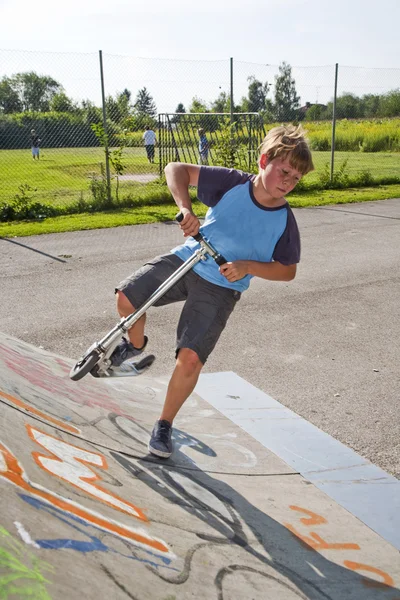 Jongen rijdt scooter in een pijp bij een skate park — Stockfoto