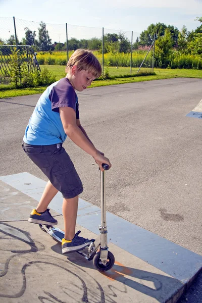 Jongen rijdt scooter in een pijp bij een skate park — Stockfoto