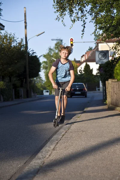 Junge fährt Roller auf Fußweg im öffentlichen Raum — Stockfoto