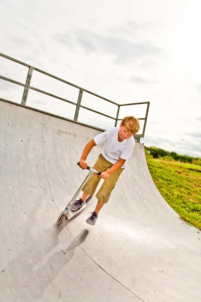 Pojke rider skoter i ett rör på en skate park — Stockfoto