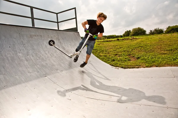 Boy rides scooter in the halfpipe — Stock Photo, Image