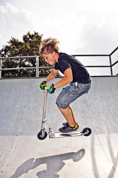 Junge fährt Roller in Rohr — Stockfoto