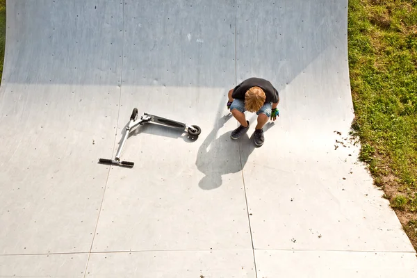Chłopiec jeździ skuterem w halfpipe — Zdjęcie stockowe