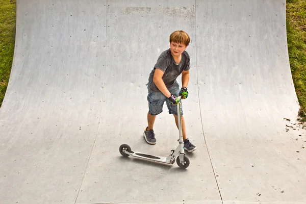 Мальчик ездит на скутере по хафпайпу — стоковое фото